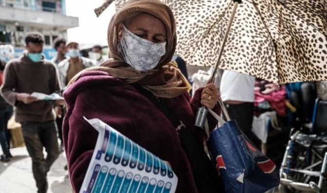 Une femme regarde un document montrant une liste de partis politiques pour les prochaines élections générales prévues le 21 juin 2021, reçu d'un personnel du Conseil électoral national d'Éthiopie (NEBE) sous un viaduc à Addis-Abeba, en Éthiopie, le 17 juin, 2021. (Yasuyoshi Chiba/ AFP)