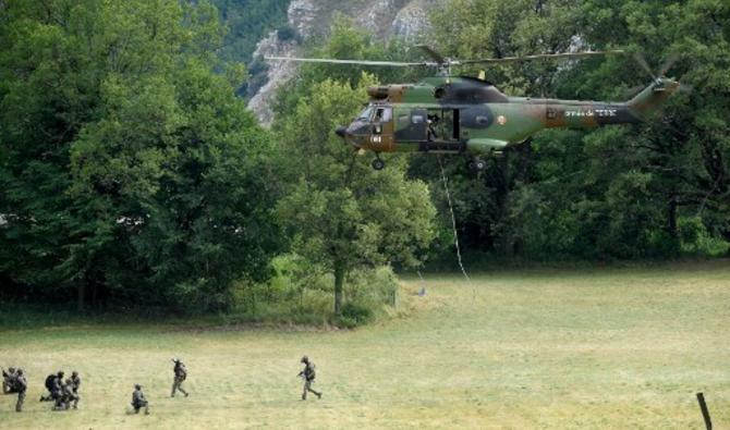 Des membres du Groupe d'intervention de la gendarmerie nationale (GIGN) se tiennent dans un champ alors qu'un hélicoptère Puma de l'Armée de Terre française atterrit à Gréolières, dans le sud-est de la France, le 19 juillet 2021 (Photo, AFP)