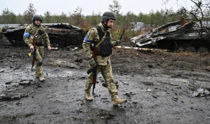 Des soldats ukrainiens passent devant l'épave de véhicules blindés russes dans le village de Dmytrivka, à l'ouest de Kiev, le 2 avril 2022. (Photo, AFP)